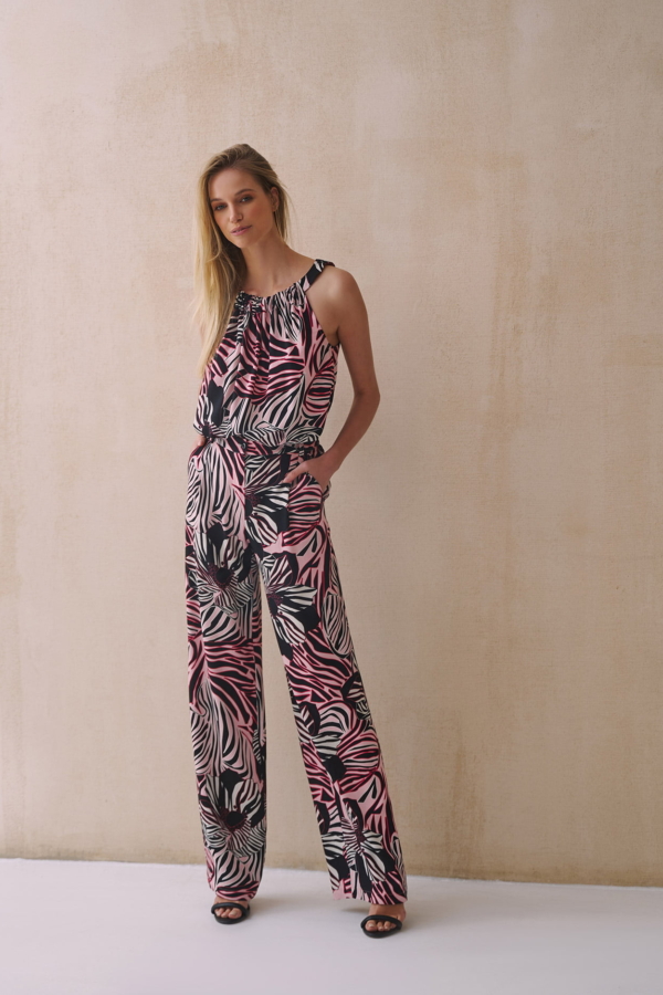 Modelka w stylowych spodniach z szeroką nogawką, wykonanych z lekkiej i przewiewnej wiskozowej tkaniny, z modnym wzorem w odcieniach różu, czerni i bieli.