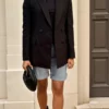 Kobieta w jasnych bermudach z cienkiego jeansu i czarnym bezrękawnikiem, w eleganckiej letniej stylizacji