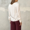 Biała bluzka damska z długim rękawem – stylizacja ze spodniami w kolorze burgundowym