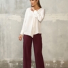 Biała bluzka damska z długim rękawem – stylizacja ze spodniami w kolorze burgundowym