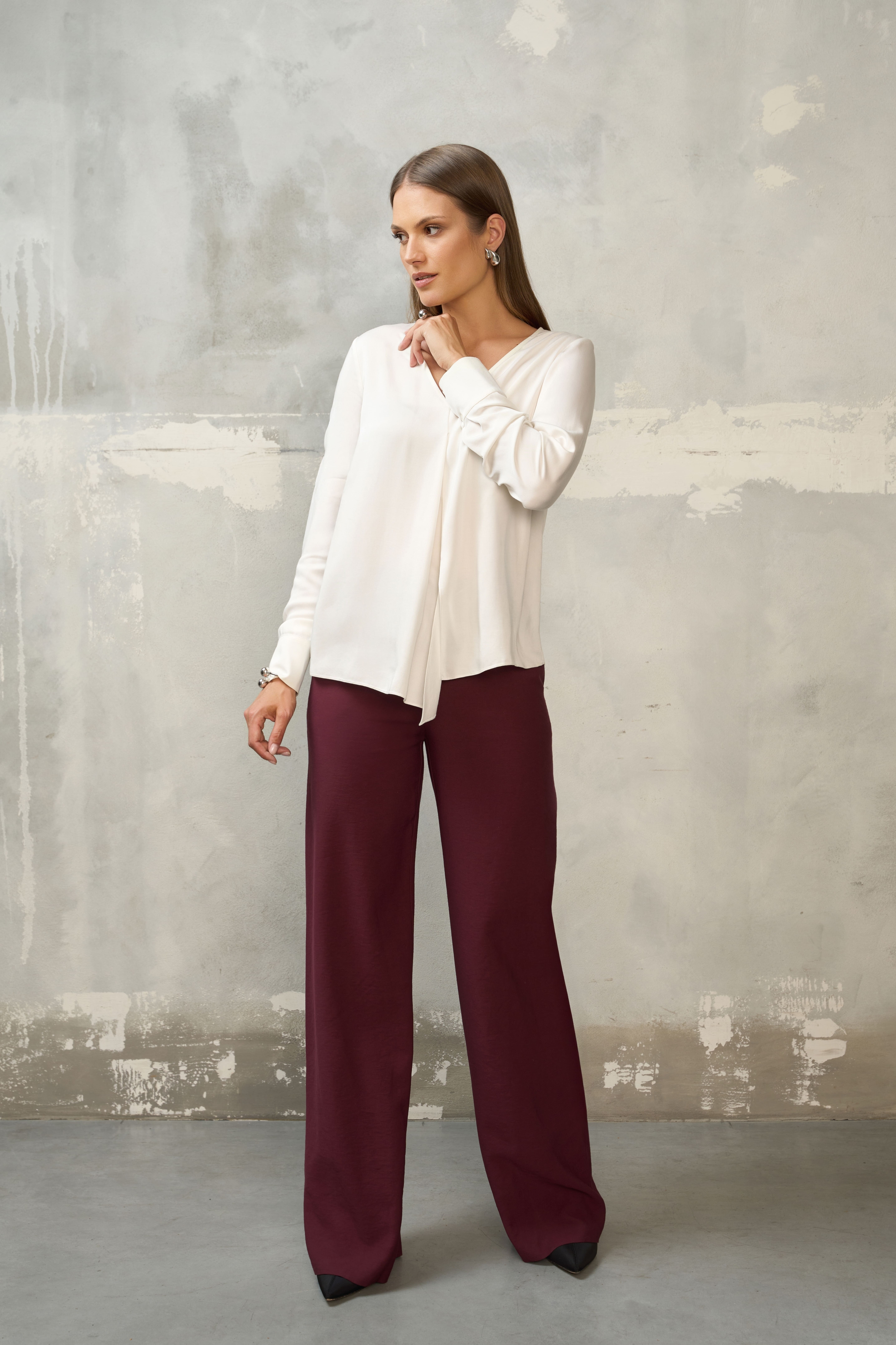Biała bluzka damska z długim rękawem – stylizacja ze spodniami w kolorze burgundowym