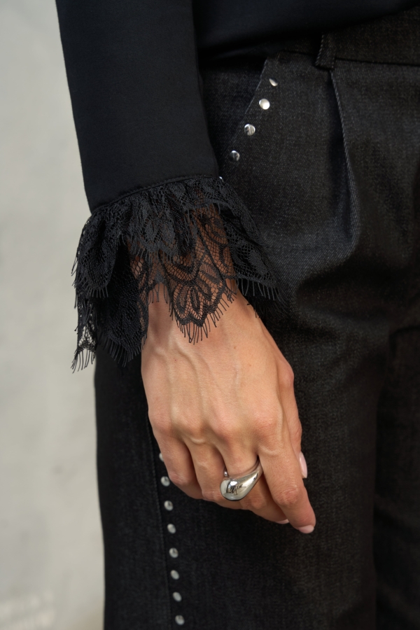 Detal koronki przy mankiecie czarnej bluzki