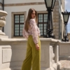Modelka w eleganckich szerokich spodniach z wysokim stanem Milano w odcieniu zgaszonej limonki, z lekko rozszerzaną nogawką i gumką z tyłu pasa.