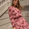 Modelka w sukience Sienna midi w różowych odcieniach z dekoltem V i długim rękawem.