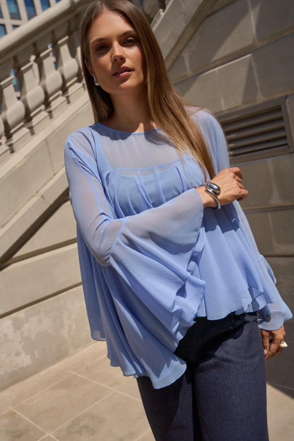 Błękitna bluzka EZURI z szerokimi, falującymi rękawami w ruchu