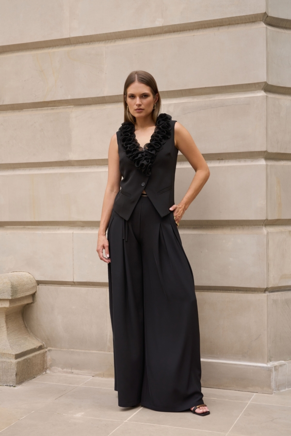Czarna elegancka kamizelka EZURI z falbaną przy dekolcie, stylizacja z szerokimi czarnymi spodniami