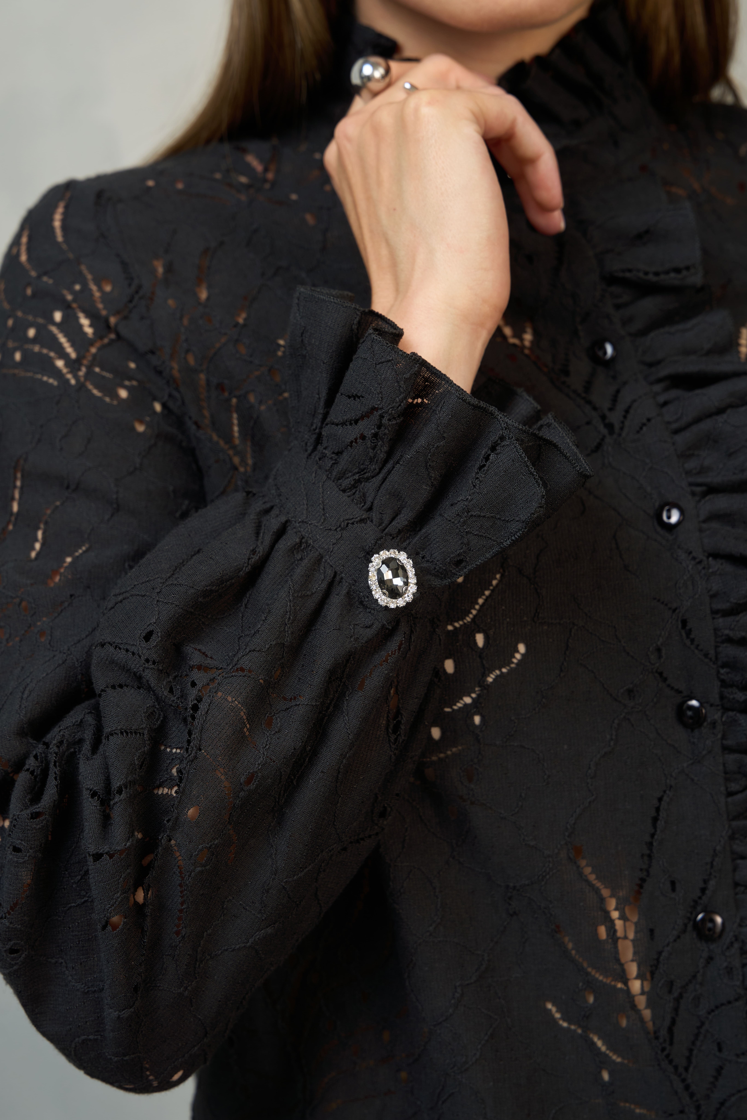 Detal mankietu z ozdobnym guzikiem w czarnej bluzce