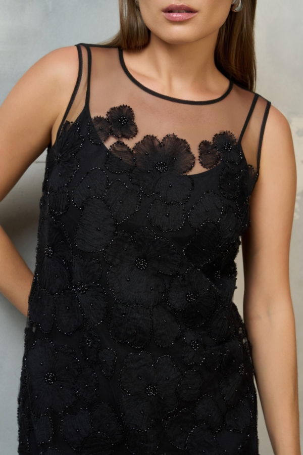 Zbliżenie na transparentny dekolt i kwiatowe koraliki.