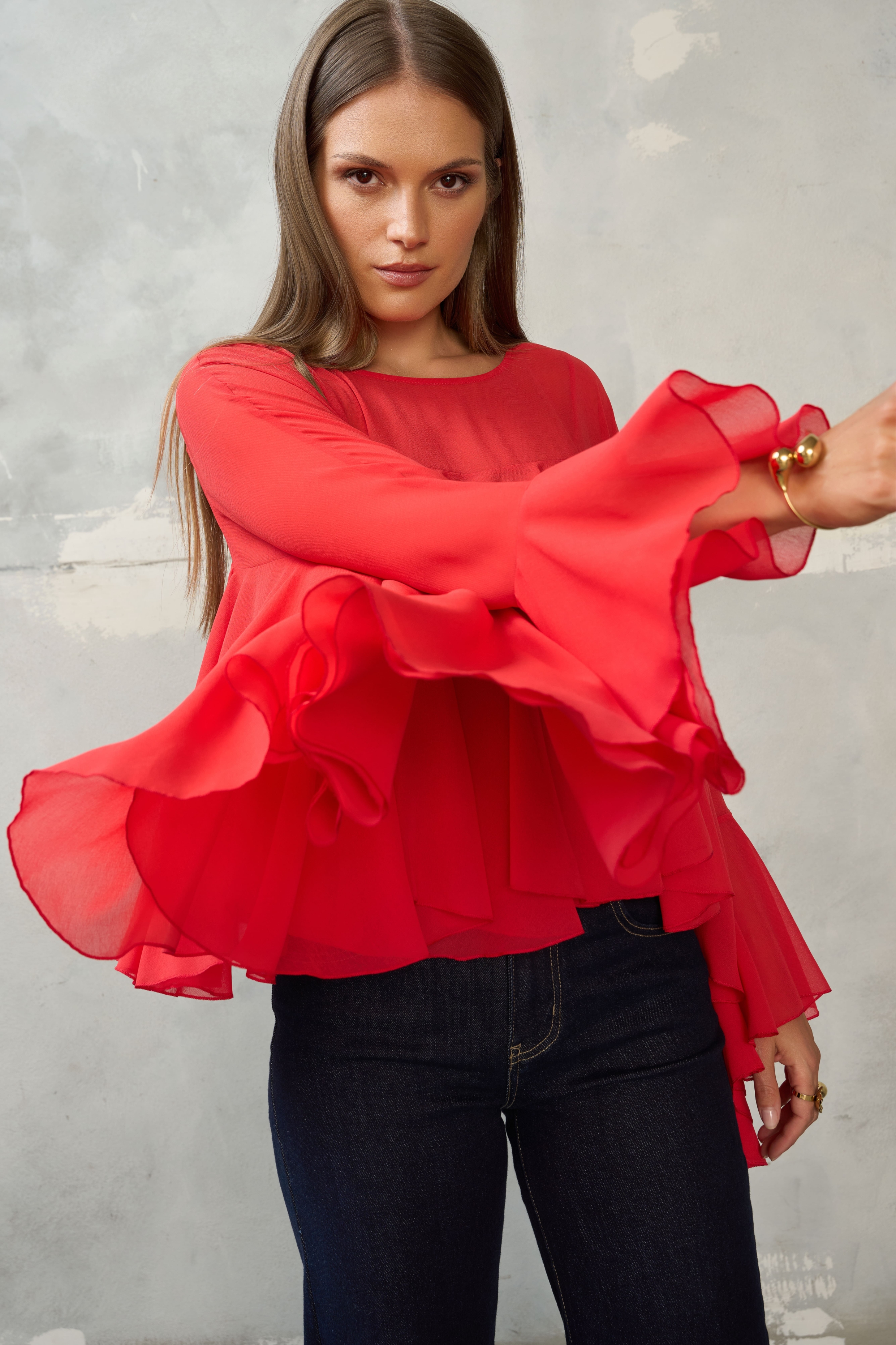 Czerwona bluzka z falbanami i szerokimi rękawami. Luźny, maskujący krój, dłuższy tył. Idealna do jeansów, na wyjście i wyjątkowe okazje.