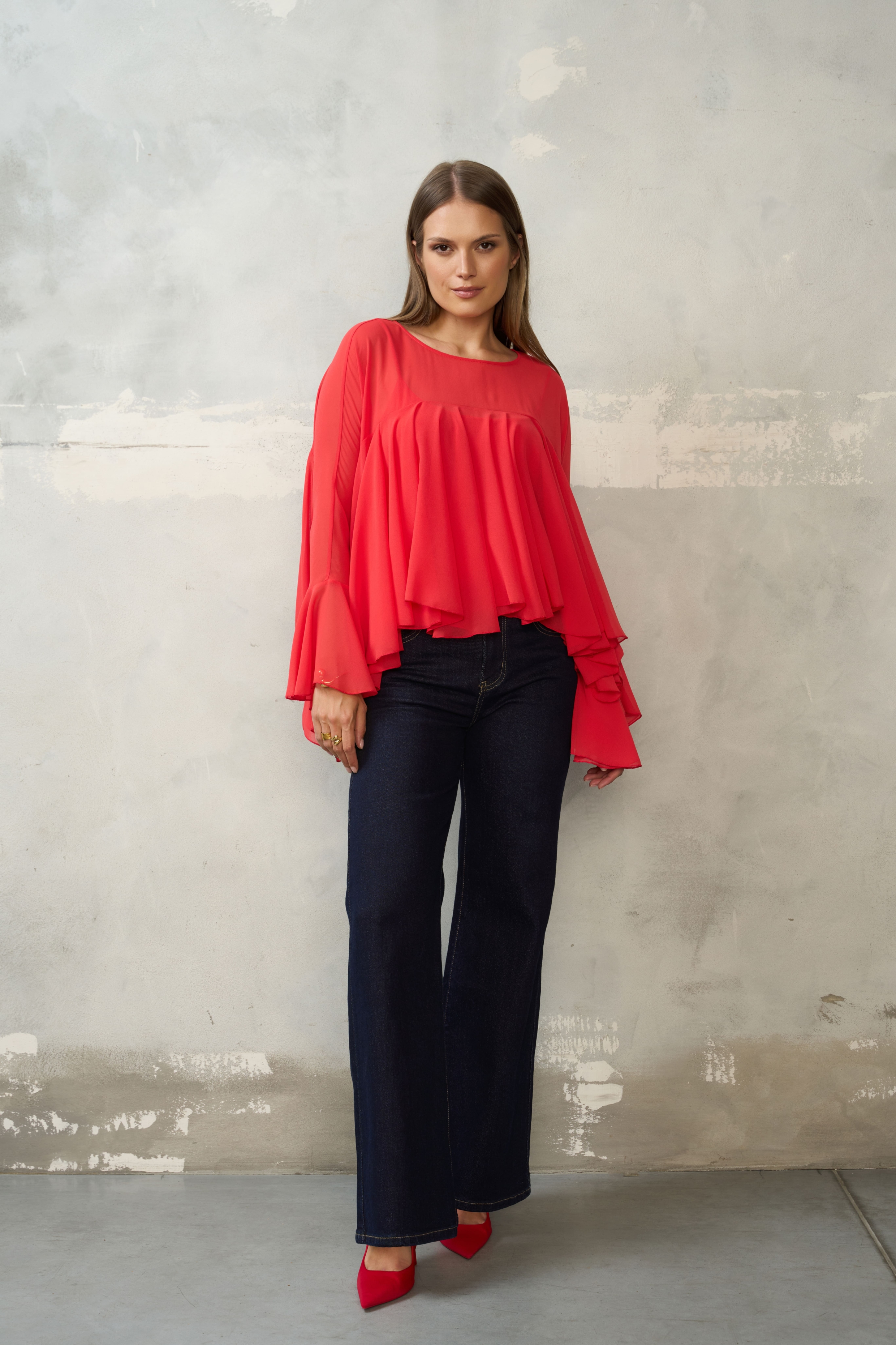 Czerwona bluzka z falbanami i szerokimi rękawami. Luźny, maskujący krój, dłuższy tył. Idealna do jeansów, na wyjście i wyjątkowe okazje.