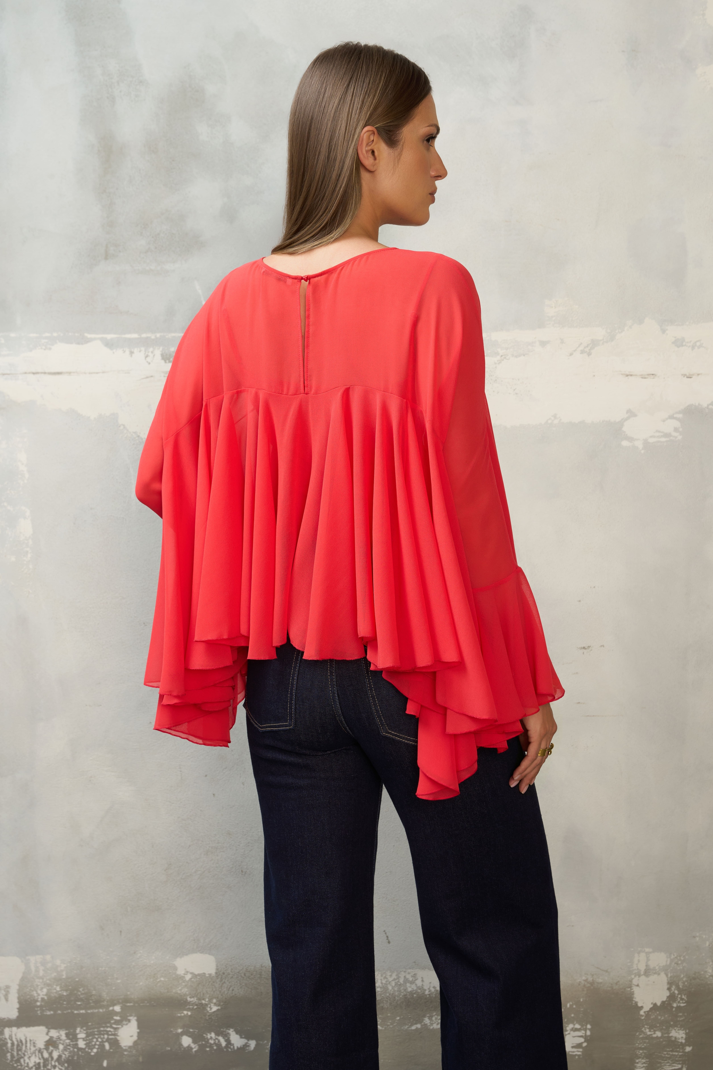 Czerwona bluzka z falbanami i szerokimi rękawami. Luźny, maskujący krój, dłuższy tył. Idealna do jeansów, na wyjście i wyjątkowe okazje.