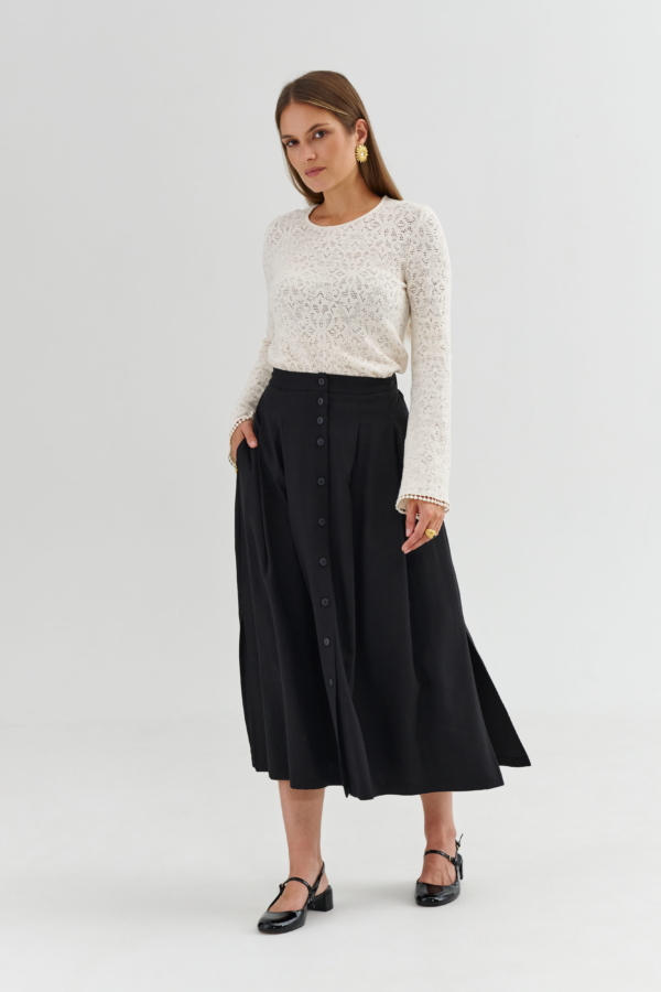 Czarna spódnica na guziki – detal zapięcia i gładkiego wykończenia
