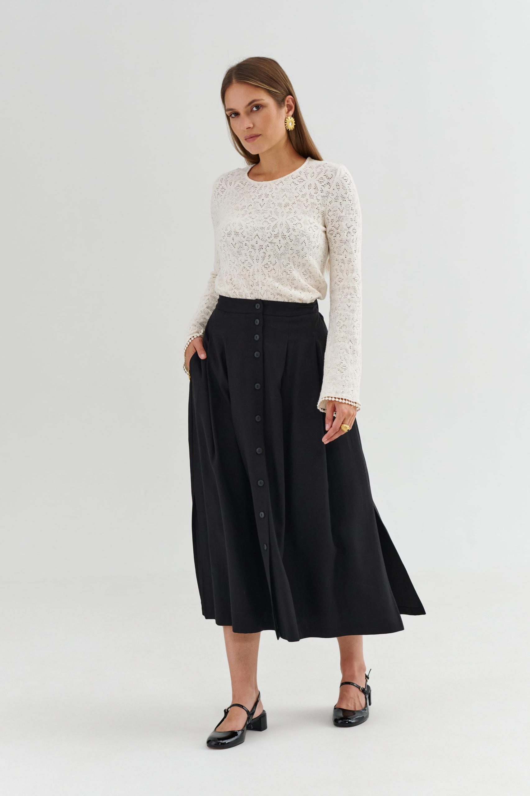 Czarna spódnica na guziki – detal zapięcia i gładkiego wykończenia