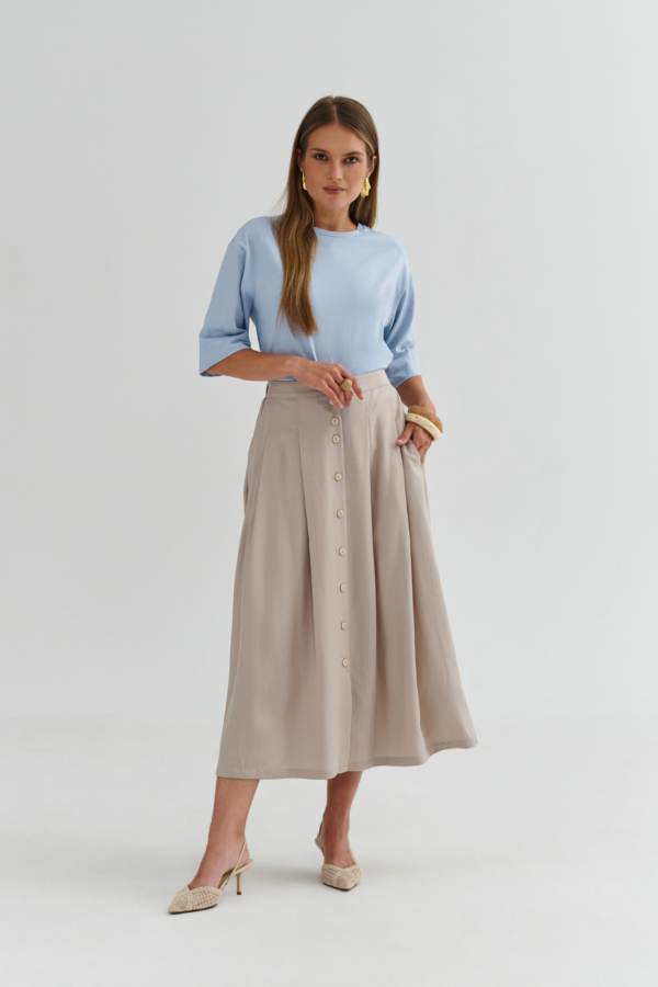 Błękitny t-shirt z dłuższym rękawem w stylizacji z beżową spódnicą midi na guziki, minimalistyczny look.