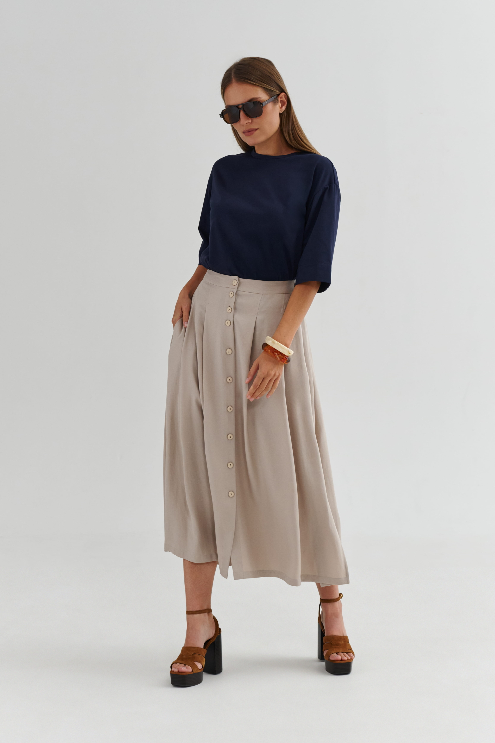 Granatowy t-shirt z dłuższym rękawem w stylizacji z beżową spódnicą midi na guziki, elegancki look na co dzień.