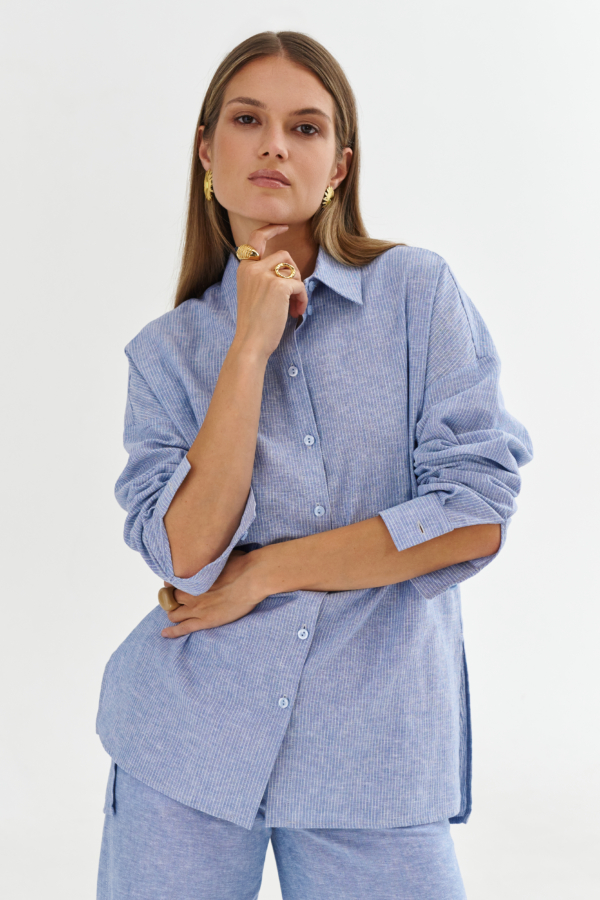 Błękitna koszula w drobne pionowe paski, lekko oversize, zapinana na guziki, długi rękaw, stylizacja ze złotą biżuterią.