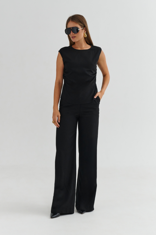 Modelka w czarnych spodniach z kieszeniami – widok z przodu, elegancki total look