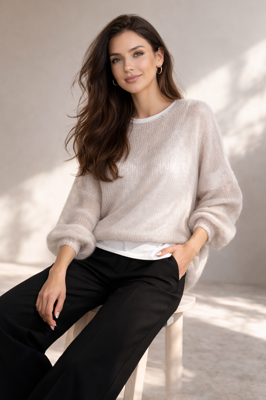 Beżowy sweter z 70% kid mohairu na modelce w czarnych szerokich spodniach – lekki, puszysty, nowoczesny krój