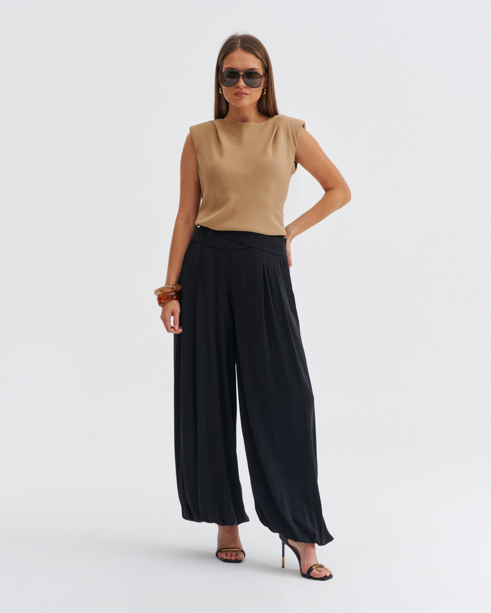 Beżowa bluzka damska bez rękawów z poduszkami na ramionach i łagodnym dekoltem.