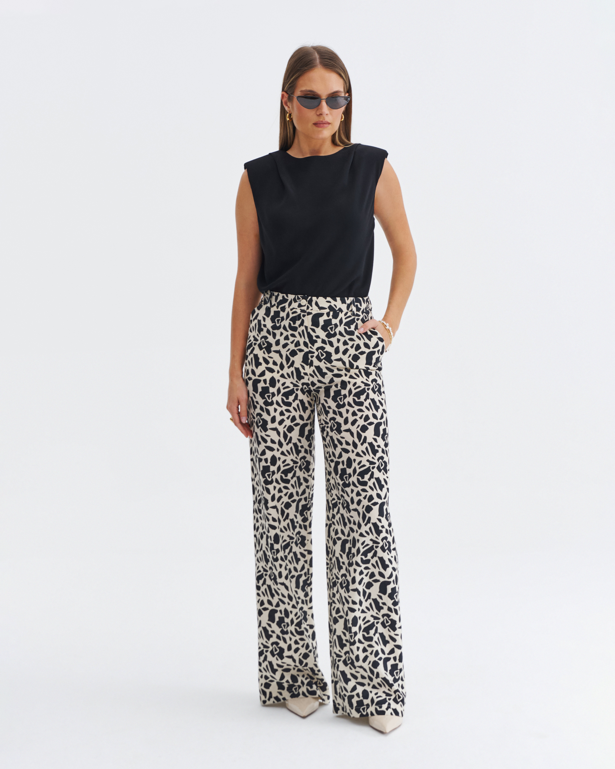 Czarna bluzka damska bez rękawów z poduszkami na ramionach i prostym krojem.