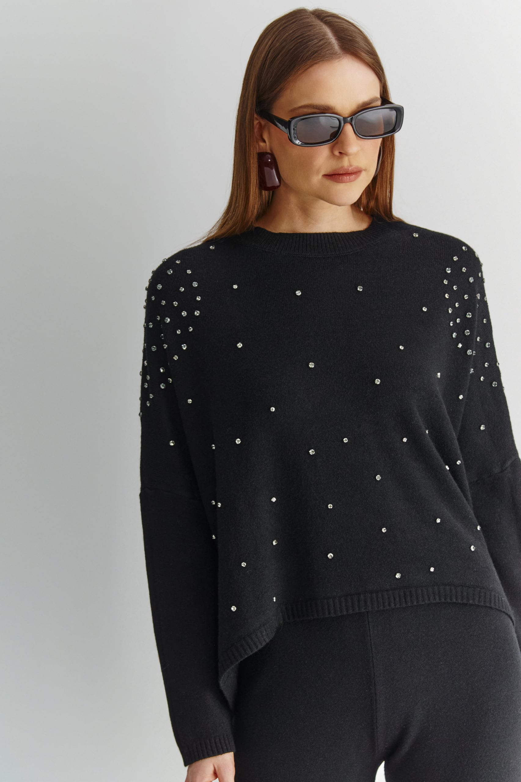 Czarny sweter damski z kryształkami w eleganckiej stylizacji z szerokimi spodniami